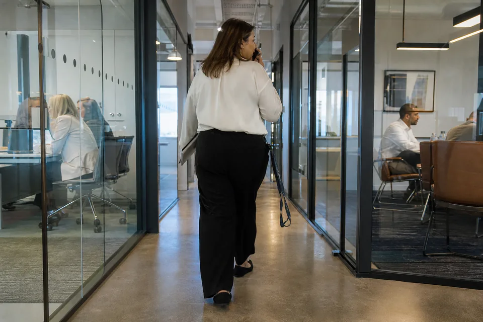 Manager walking along an office corridor between meetings, speaking into her phone